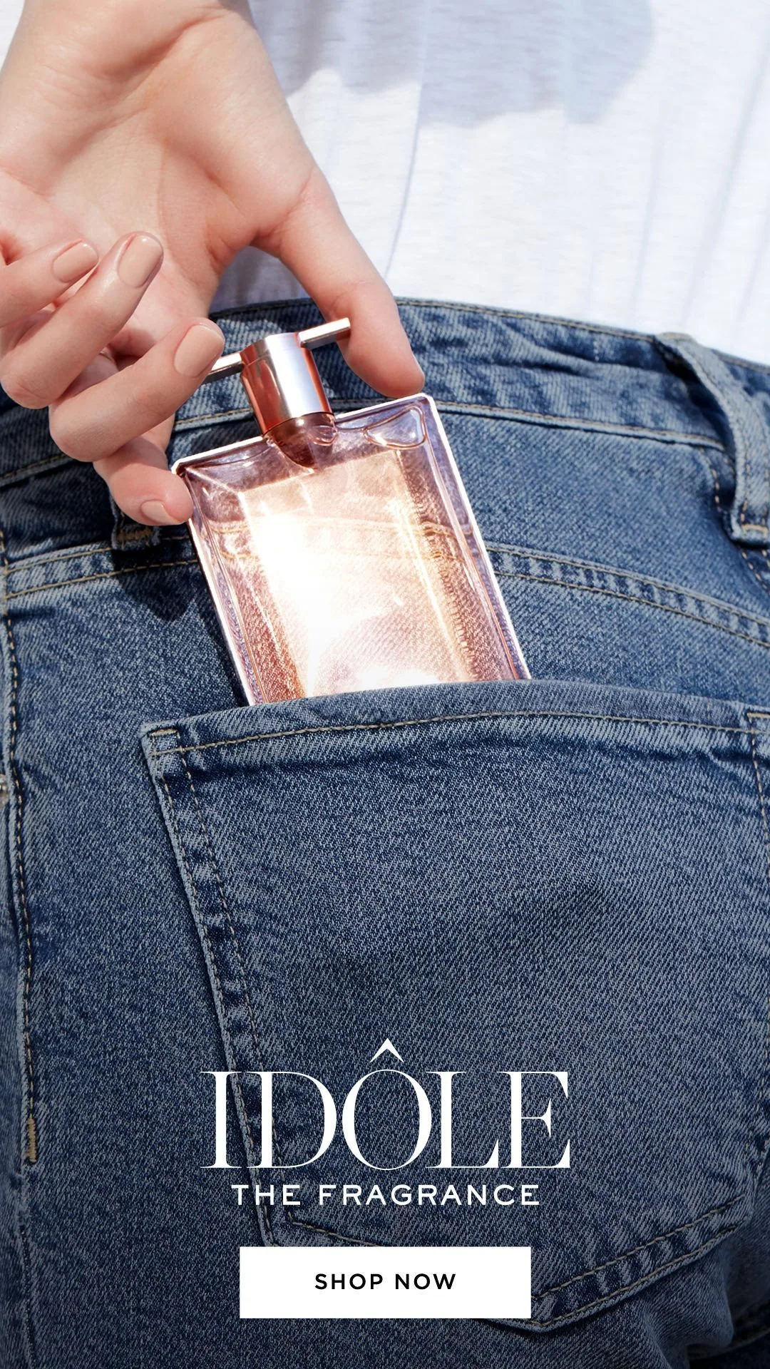 Hand placing a perfume bottle into jeans pocket